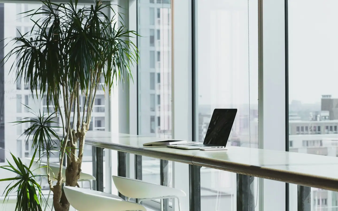 Sunlit city-view workspace with a laptop on a window bar